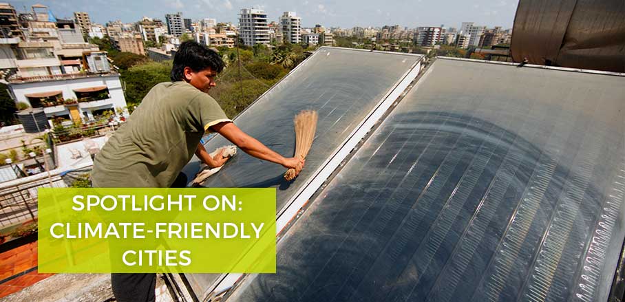 Housekeeper cleans solar thermal panels for a hot water installation on a roof of an apartment block in Juhu, Mumbai, India © The Climate Group (Flickr CC BY-NC-SA 2.0)
