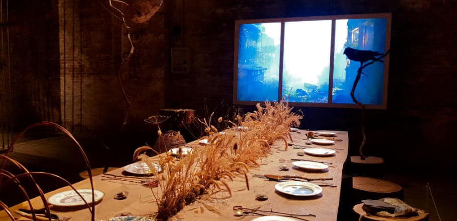 A set dinner table. In the background a screen that looks like a window.