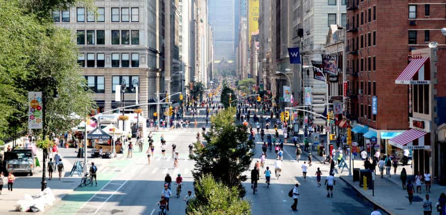 On a beautiful summer's day, cyclists and pedestrians are walking on streets usually filled with cars.