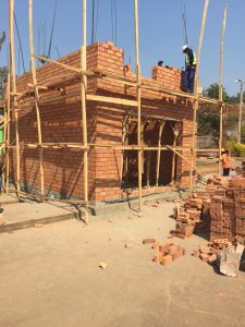A construction site showing a cube house made of bricks