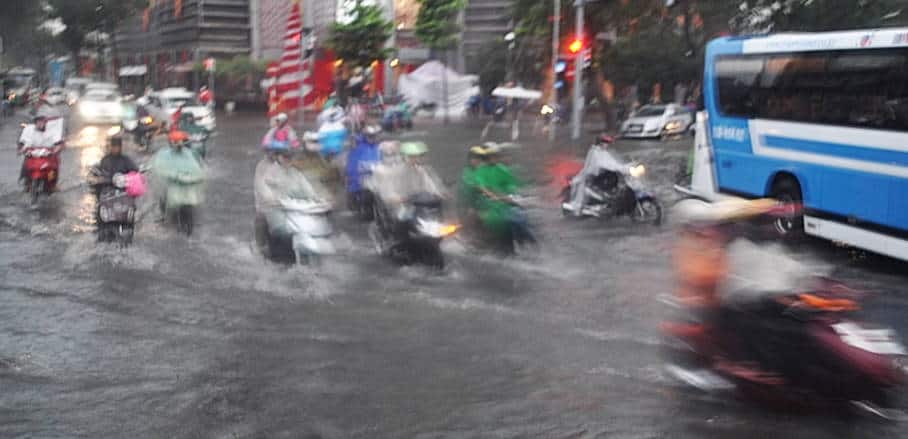Motorbikes and a public bus driving on a flooded street in Ho Chi Minh City, Vietnam
