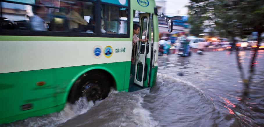 A bus trying to make its way through a heavily flooded street