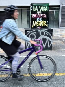 A woman on a bicycle is riding past as sign that says 