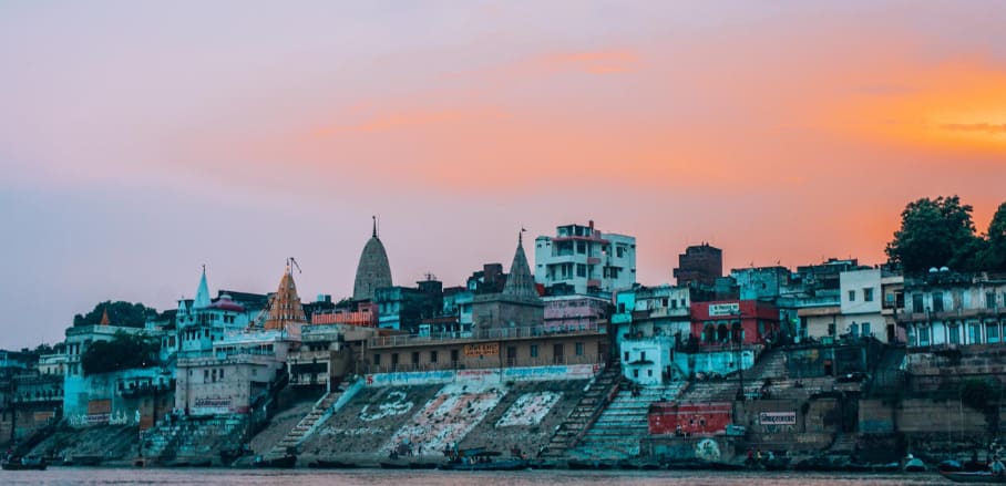 An Indian city on the riverbank at sunrise.