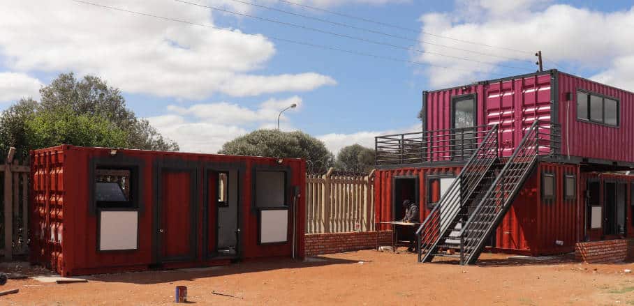 The photo shows multiple red and pink painted shipping containers.